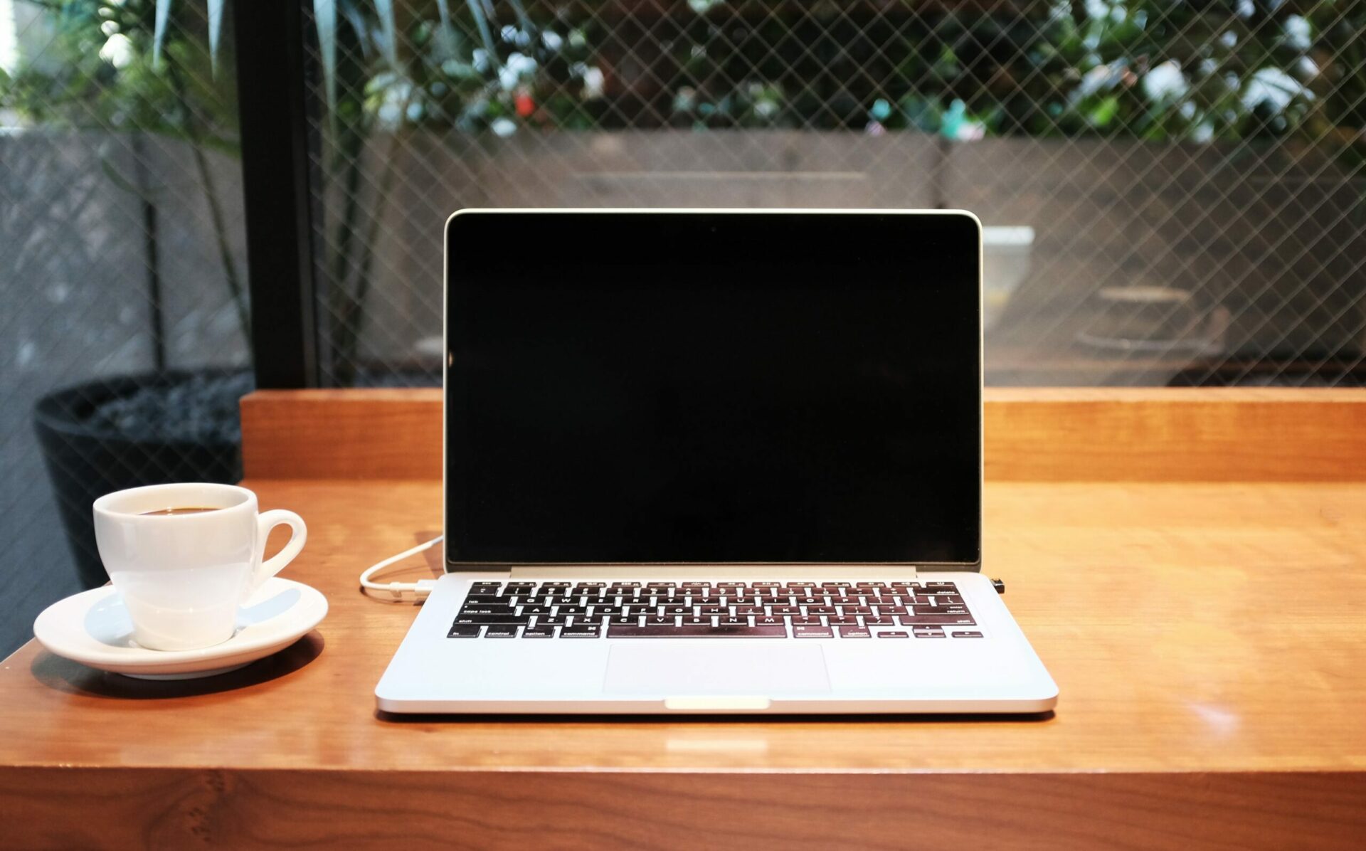 Blank laptop on wooden desk with white coffee cup